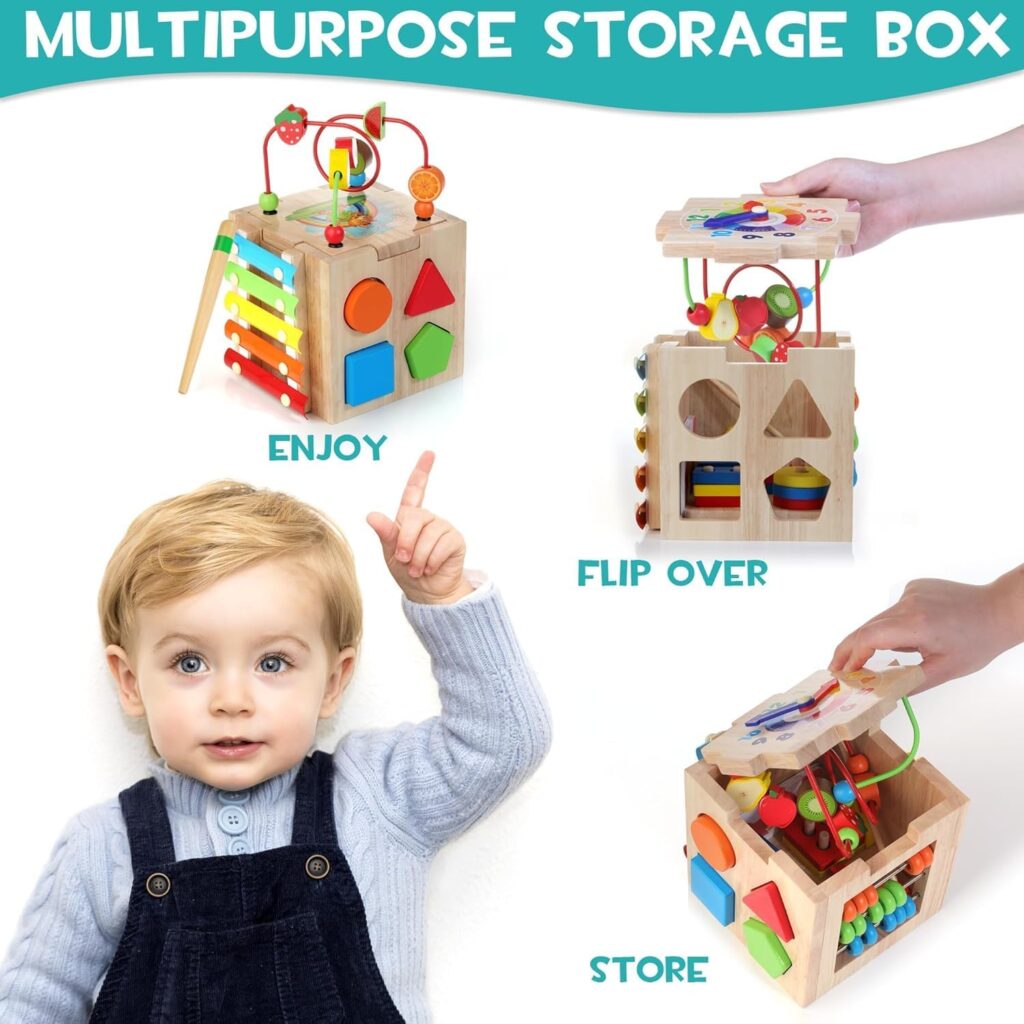 A wooden multipurpose activity cube for toddlers is shown with different sides featuring colorful shape sorters, xylophone bars, bead mazes, and spinner toys. One image shows the cube being used with the bead maze on top labelled “ENJOY.” Another shows a hand flipping the top upside down to reveal storage inside, labeled “FLIP OVER.” A third shows toys being stored inside the cube, labelled “STORE.” A smiling young child points upward toward the activity cube. The text at the top reads “MULTIPURPOSE STORAGE BOX.”