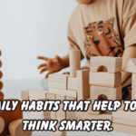 A toddler sitting on the floor and playing with natural wooden blocks and stacking toys. The text on the image reads “Easy Daily Habits That Help Toddlers Think Smarter.”